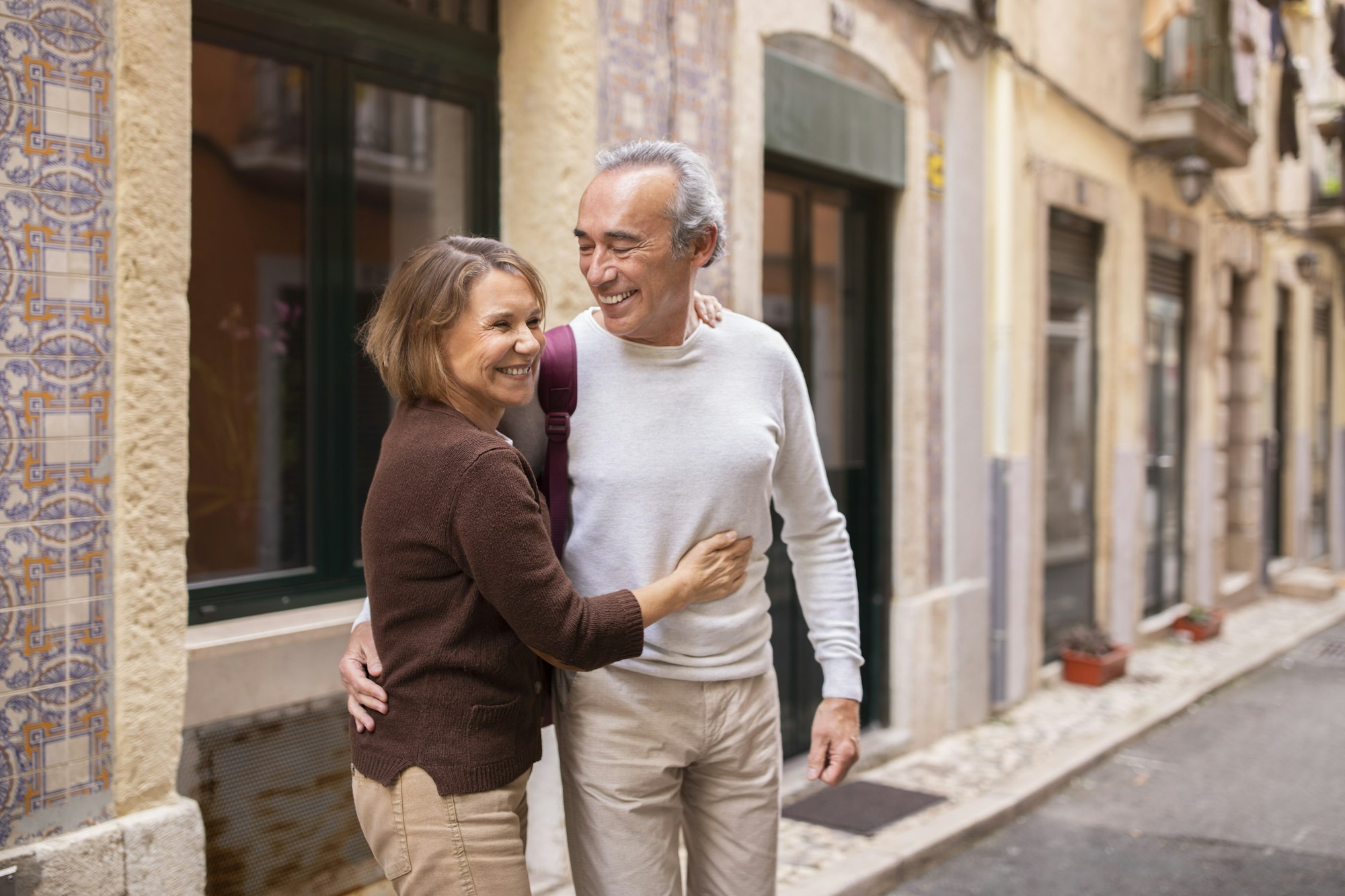 Smiling European Pensioners Couple Embracing Standing Outside On Lisbon Street