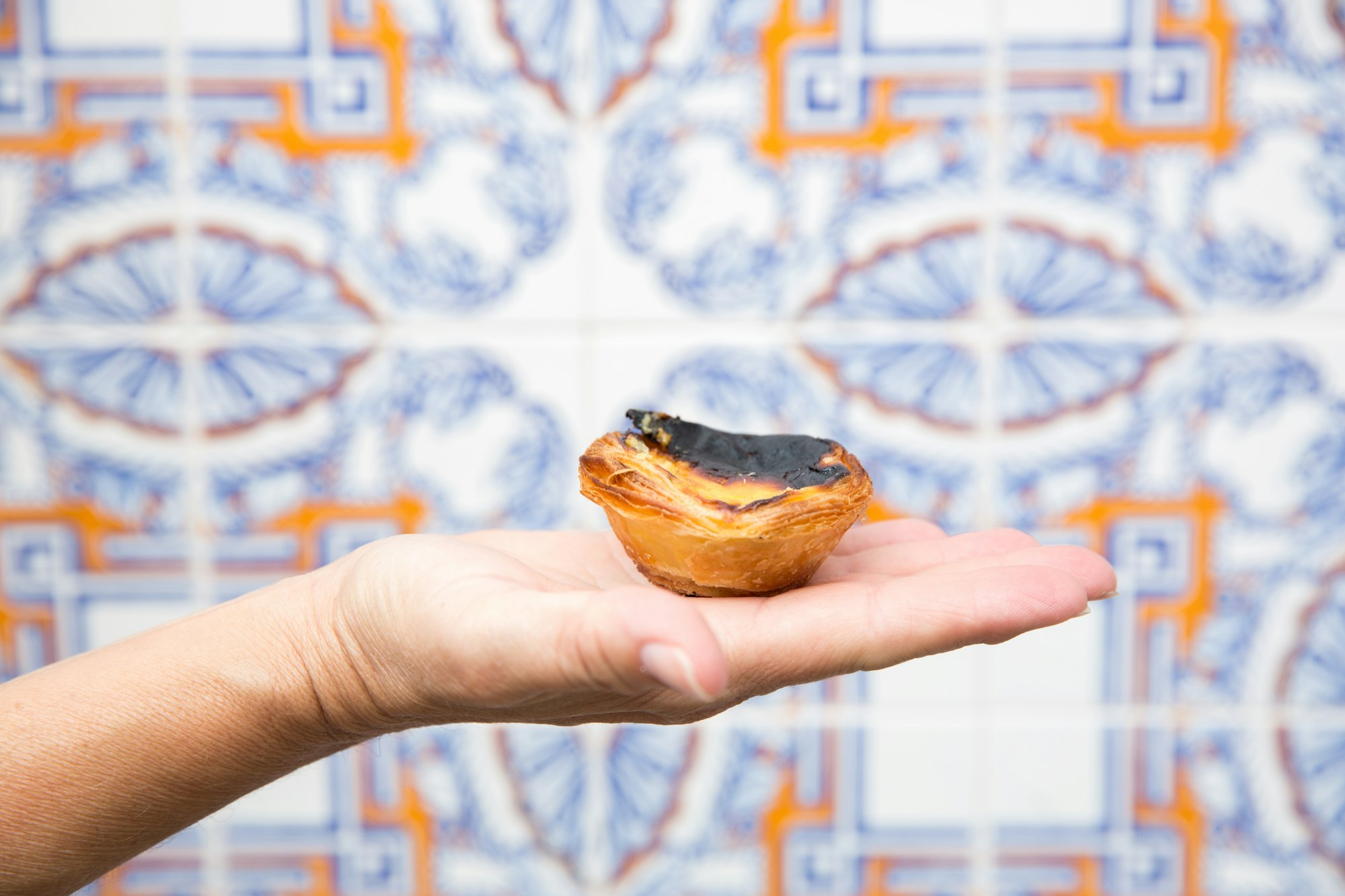 A hand holding a pastel de nata in Lisbon, Portugal.